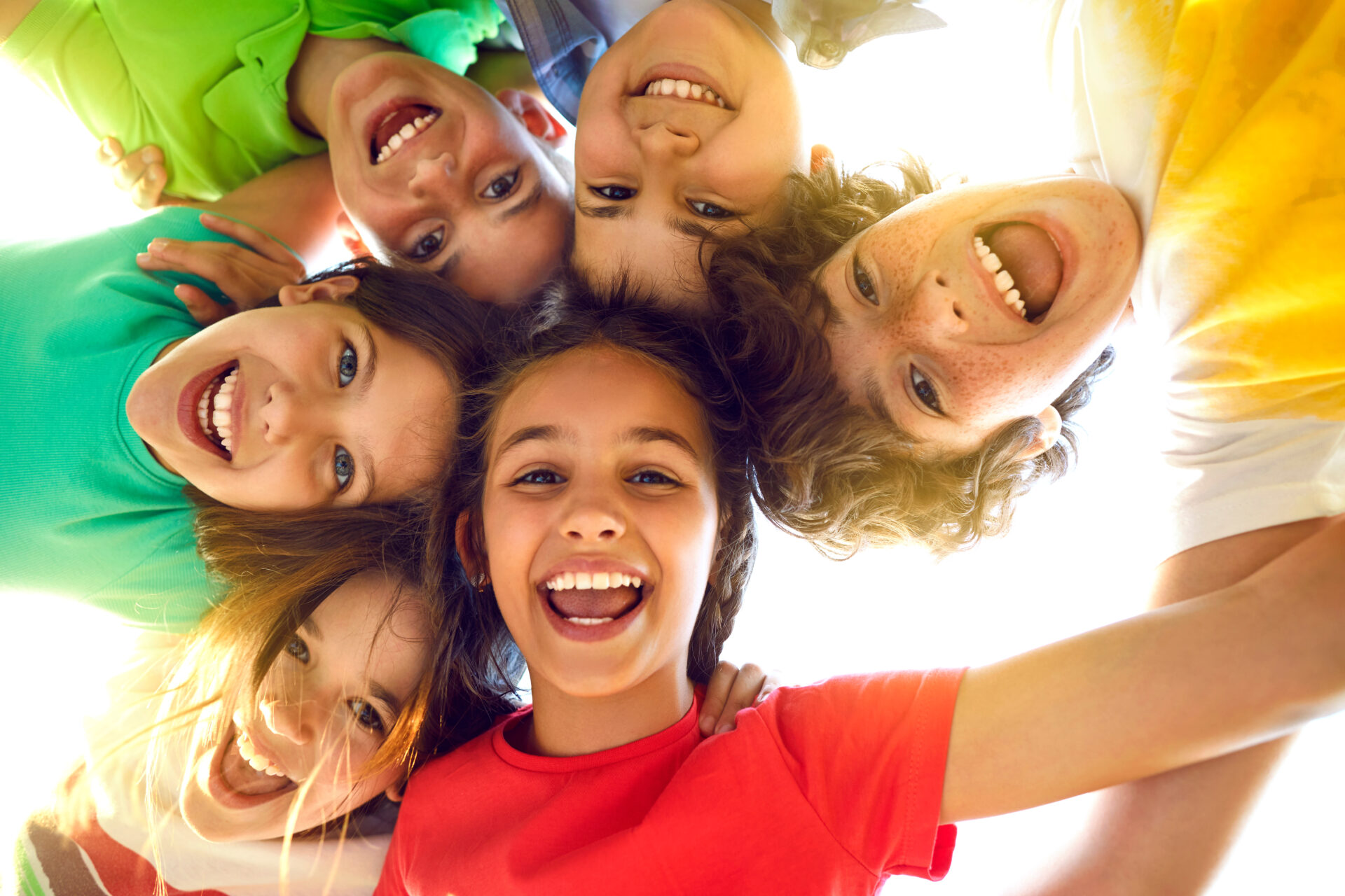 Group of happy little children playing together, having fun, huddling, looking down and smiling Group of happy little children playing together, having fun, huddling, looking down and smiling
